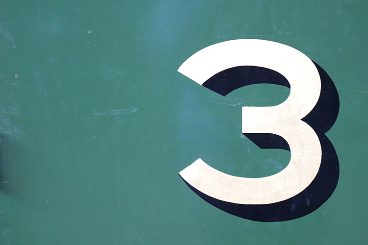 Un redondo número 3 dibujado en una fachada color verde.